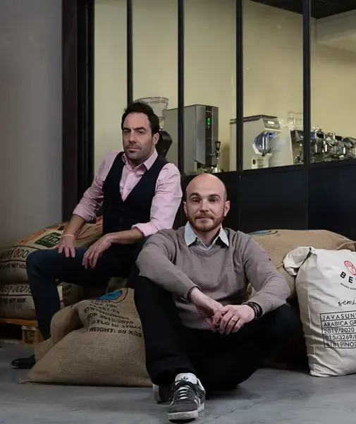 Photo des deux fondateurs de café toqué assis sur des sacs de jute