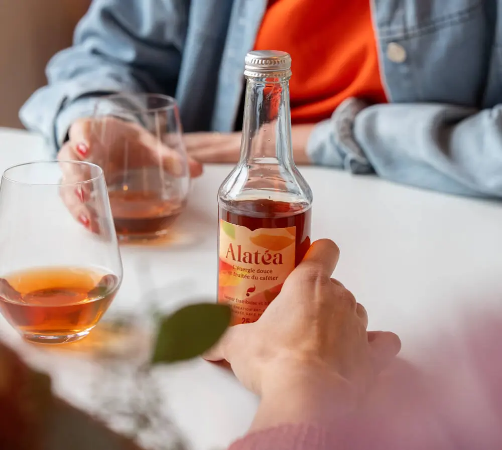 Aperçu d'une bouteille d'Alatéa tenue en main et posée sur une table